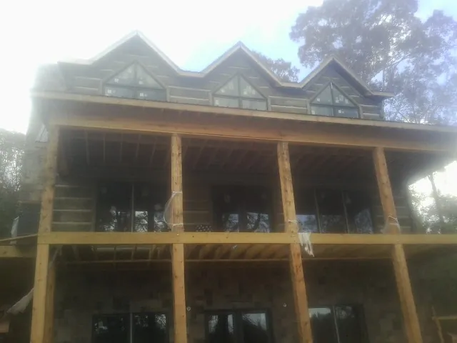 Dormers and porch framing on a large log home under construction — Roof Coating work by our crew in Summerdale