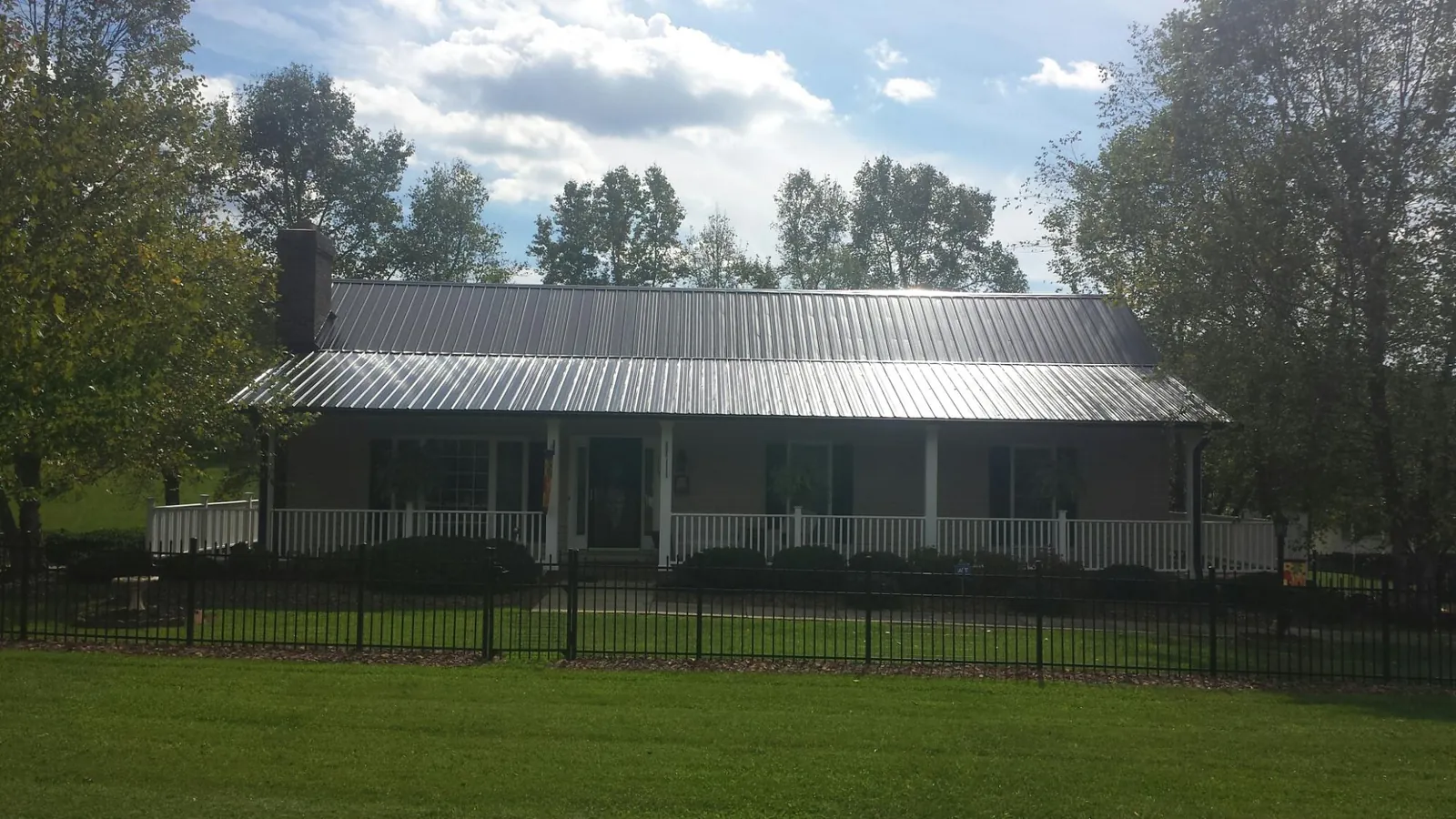 Gray metal roof on a brick ranch with a full width front porch — Gutter Guard Installation work by our crew in Summerdale