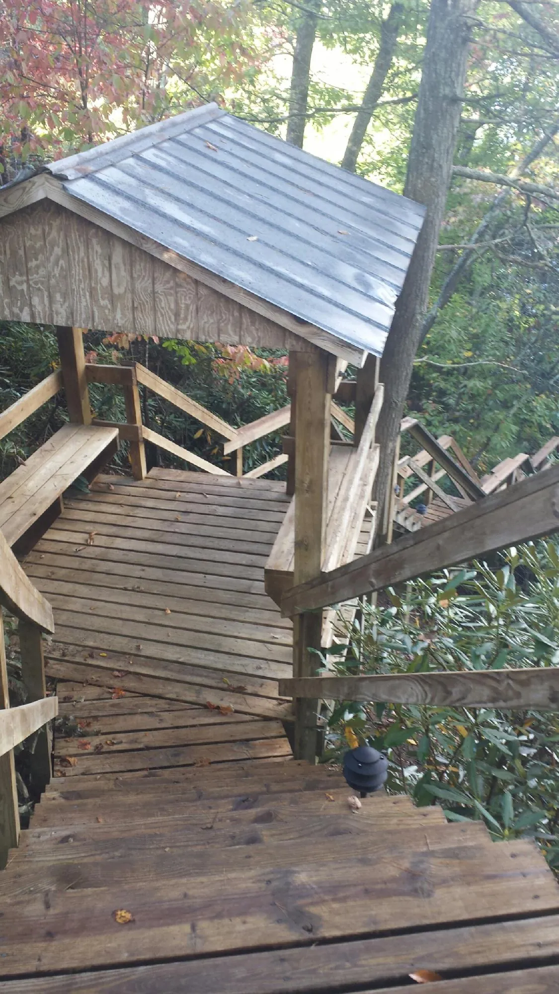 Metal roofed shelter over wooden steps on a wooded walkway — Skylight Repair & Installation work by our crew in Summerdale
