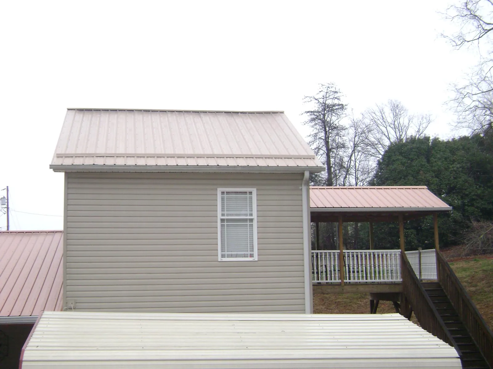 Tan metal roofs on a two story addition and attached porch, from a Roof Replacement job in Summerdale