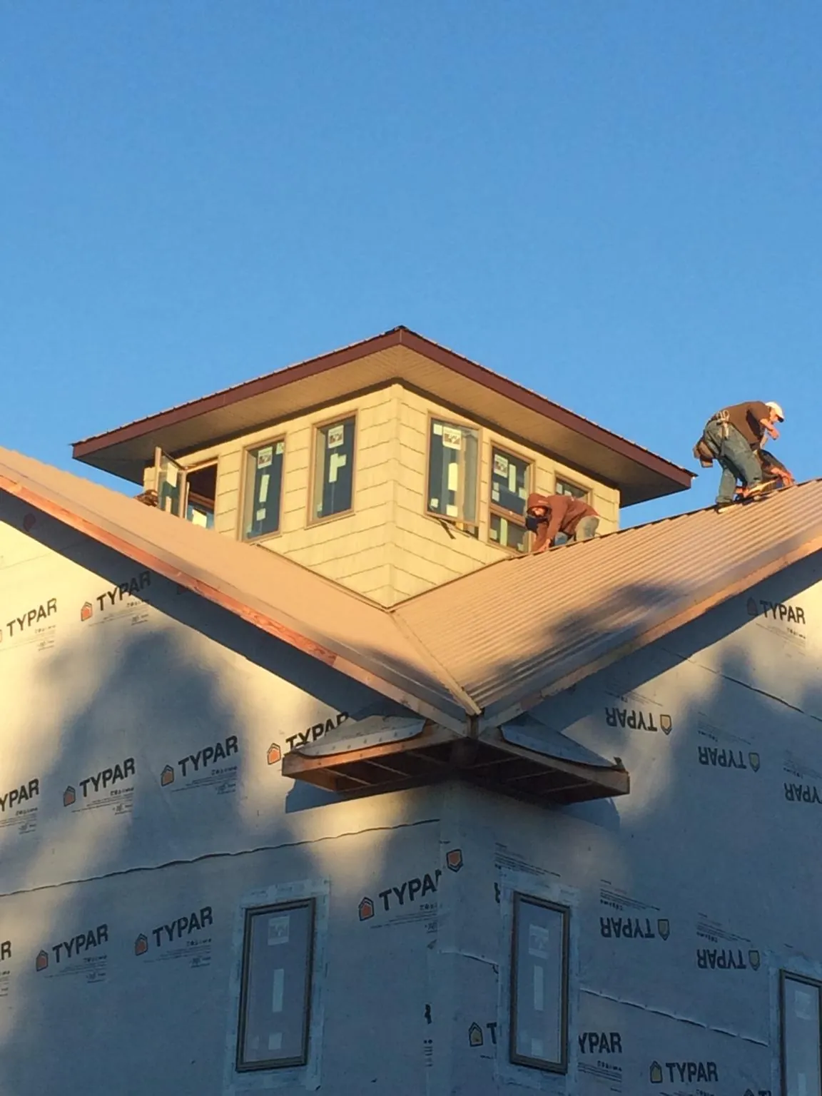 Roofers working around a rooftop cupola on a new metal roof at sunset — Roof Waterproofing in Summerdale by Roofing Brothers